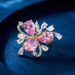 Crystal flower brooch wholesale featuring three prominent teardrop CZ petals surrounded by pavé ribbons and marquise crystal accents in gold plating from junejewelry.com