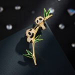 Panda bamboo brooch wholesale featuring two pavé cubic zirconia pandas clinging to a gold-plated bamboo stalk with green enamel leaves from junejewelry.com