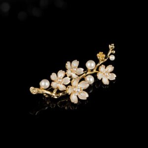 Delicate plum blossom pearl brooch wholesale featuring enamel floral petals, cz crystal pistils, and pearl accents on a gold-plated branch from junejewelry.com