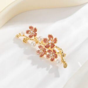 Delicate plum blossom pearl brooch wholesale featuring enamel floral petals, cz crystal pistils, and pearl accents on a gold-plated branch from junejewelry.com