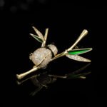 Playful Chinese style panda bamboo branch CZ brooch wholesale featuring a micro-pave cubic zirconia panda hugging a gold-plated bamboo stalk with green enamel and pave crystal leaves from junejewelry.com