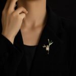 Playful Chinese style panda bamboo branch CZ brooch wholesale featuring a micro-pave cubic zirconia panda hugging a gold-plated bamboo stalk with green enamel and pave crystal leaves from junejewelry.com
