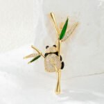 Playful Chinese style panda bamboo branch CZ brooch wholesale featuring a micro-pave cubic zirconia panda hugging a gold-plated bamboo stalk with green enamel and pave crystal leaves from junejewelry.com