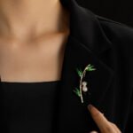 Playful Chinese style panda bamboo CZ brooch wholesale featuring a micro-pave cubic zirconia panda climbing a gold-plated bamboo stalk with vibrant green enamel leaves from junejewelry.com