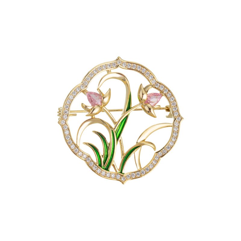 Orchid brooch wholesale featuring a circular micro-pavé frame enclosing pink enamel orchid blossoms and green enamel leaves in gold plating from junejewelry.com