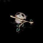 Panda brooch wholesale featuring micro-pavé cubic zirconia panda hugging a gold bamboo stalk with marquise emerald green crystal leaves from junejewelry.com