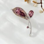 Crystal flower brooch wholesale featuring faceted teardrop glass petals bordered by multi-colored paved rhinestones on an elegant stem in silver plating from junejewelry.com