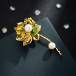 Oriental luxury Chinese style enamel lotus pearl brooch wholesale featuring translucent enamel petals, yellow enamel stamens, micro-pave CZ outlines, and dual freshwater pearls on a gold stem from junejewelry.com