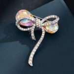 Iridescent bow brooch wholesale featuring faceted rainbow AB glass crystal loops and pave rhinestone ribbon borders in silver plating from junejewelry.com