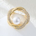 Geometric round pearl brooch wholesale featuring interlocking polished metal and micro-pavé cubic zirconia swirl rings framing a round center pearl from junejewelry.com