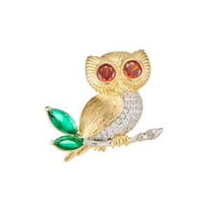 Crystal owl brooch wholesale featuring amber cubic zirconia eyes, green crystal leaf tail accents, pavé CZ wing, and texturing sitting on a branch from junejewelry.com