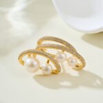 Light luxury layered pearl cluster brooch wholesale featuring multi-tiered micro-pave cubic zirconia curved bands nestled with lustrous white pearls from junejewelry.com