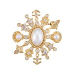 Light luxury unisex nautical pearl star anchor CZ brooch wholesale featuring a large oval pearl centerpiece framed by a starburst of anchors, sea shells, star-cut crystals, and paved cubic zirconia in gold or silver finish from junejewelry.com