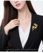 Elegant bamboo leaf pearl brooch wholesale featuring textured metallic leaves, a pavé cubic zirconia curved bamboo stalk, a sparkling solitaire round CZ accent, and a glossy pearl drop from junejewelry.com