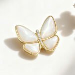 Elegant magnetic mother of pearl butterfly brooch wholesale featuring natural white or black shell wings, micro-pave cubic zirconia body, and a fabric-safe pinless magnetic back clasp from junejewelry.com