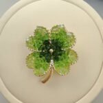 Elegant magnetic four leaf clover crystal brooch wholesale featuring four clover petals filled with crushed ice crystals and bi-color center accents, with a pinless magnetic back clasp from junejewelry.com