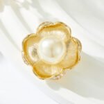 Pearl flower brooch wholesale featuring five brushed gold textured petals trimmed with micro-pavé cubic zirconia and a large center faux pearl from junejewelry.com