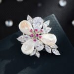 High-end baroque pearl flower CZ brooch wholesale featuring iridescent teardrop baroque shell petals, brilliant pear and marquise cubic zirconia stones, and detailed central stamens from junejewelry.com