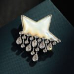 Star raindrop brooch wholesale featuring a smooth white mother-of-pearl shell star with dangling teardrop and round cubic zirconia raindrops from junejewelry.com