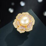 High-end magnetic camellia CZ pearl brooch wholesale featuring micro-pave white and purple cubic zirconia petals, a luminous glass pearl center, and a strong pinless magnetic back clasp in gold or rhodium finish from junejewelry.com