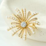 Dazzling firework pearl crystal brooch wholesale featuring radiating metallic rays set with round pearls and pave cubic zirconia centered around a brilliant jewel gemstone, with convertible pendant hook functionality from junejewelry.com