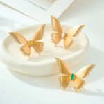 Brushed gold butterfly brooch wholesale featuring textured matte wings with cubic zirconia paved edges and a teardrop center stone from junejewelry.com