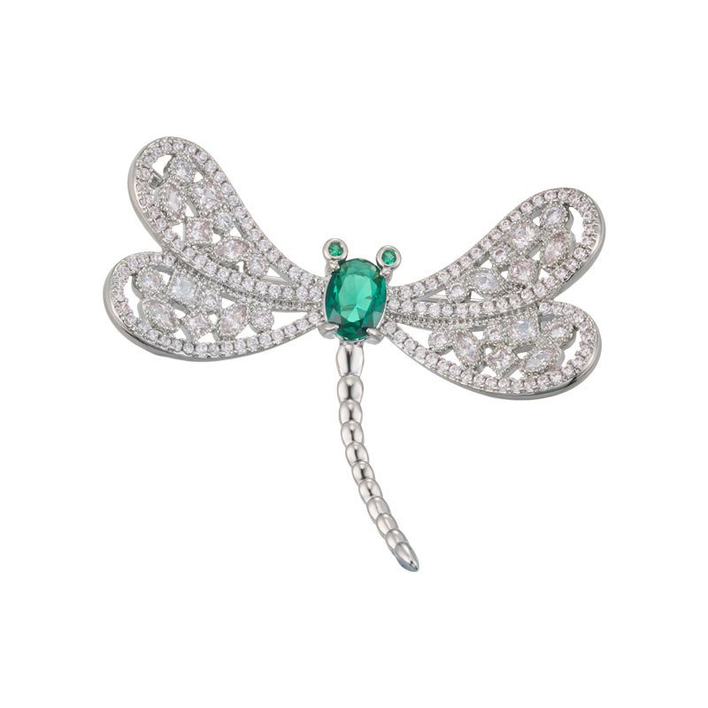 Dragonfly brooch wholesale featuring openwork filigree wings set with clear cubic zirconia, an oval gemstone body, and green CZ eyes from junejewelry.com