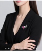 Flying bird crystal brooch wholesale featuring pavé ruby pink cubic zirconia body, clear CZ inner wings, and black enamel feather trim from junejewelry.com