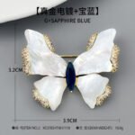 Shell butterfly brooch wholesale featuring iridescent mother-of-pearl wings with cubic zirconia paved edges and a marquise-cut center stone from junejewelry.com