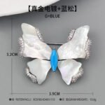 Shell butterfly brooch wholesale featuring iridescent mother-of-pearl wings with cubic zirconia paved edges and a marquise-cut center stone from junejewelry.com