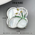 Vintage style four leaf clover mother of pearl orchid brooch wholesale featuring a natural white mother of pearl clover base overlaid with green enamel orchid leaves and a freshwater pearl flower center in gold or silver finish from junejewelry.com