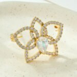 Light luxury hollow flower CZ brooch wholesale featuring pave cubic zirconia openwork petals, 14K gold or platinum color plating, and a large central teardrop pear-cut stone from junejewelry.com