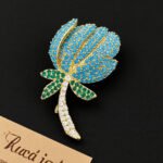 High-end turquoise protea flower CZ brooch wholesale featuring pave turquoise stone petals, green cubic zirconia leaves, and a clear pave crystal stem from junejewelry.com