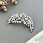 Sparkly silver curved floral CZ cluster brooch wholesale featuring brilliant pear-cut, marquise-cut, and round cubic zirconia stones in an arching vine design from junejewelry.com