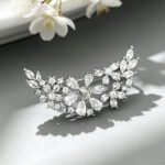 Sparkly silver curved floral CZ cluster brooch wholesale featuring brilliant pear-cut, marquise-cut, and round cubic zirconia stones in an arching vine design from junejewelry.com
