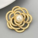 Elegant camellia flower pearl brooch wholesale featuring layered hollow micro-pave cubic zirconia petals centered with a round gray, white, or champagne glass pearl from junejewelry.com