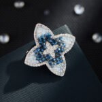 Vintage style four petal blue crystal brooch wholesale featuring gradient light and dark blue crystal beads, clear micro-pave CZ outer halo, and a center crystal cross motif from junejewelry.com