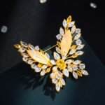 Elegant butterfly shell crystal brooch wholesale featuring carved natural shell inner wings framed by marquise cubic zirconia crystal clusters and a convertible dual-hook back pin from junejewelry.com