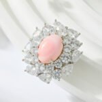 Light luxury pink queen conch shell magnetic brooch wholesale featuring an oval pink shell center surrounded by brilliant round and pear-cut cubic zirconia crystals with a strong magnetic clasp from junejewelry.com