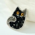 Cute and sparkling black crystal cat brooch wholesale featuring a cat silhouette studded with faceted black resin crystals, micro-pave cubic zirconia border, and vibrant amber eyes from junejewelry.com