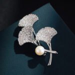 Ginkgo leaf pearl brooch wholesale featuring three pavé cubic zirconia fan-shaped ginkgo leaves, a smooth freshwater pearl accent, and a convertible back hook from junejewelry.com