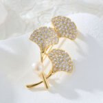 Ginkgo leaf pearl brooch wholesale featuring three pavé cubic zirconia fan-shaped ginkgo leaves, a smooth freshwater pearl accent, and a convertible back hook from junejewelry.com