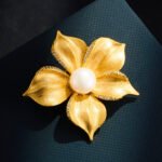 Vintage brushed gold flower pearl brooch wholesale featuring wire-brushed matte gold petals, micro-pave cubic zirconia edges, and a large central white freshwater pearl from junejewelry.com