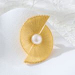 Minimalist brushed gold fan-shaped pearl brooch wholesale featuring dual wire-brushed geometric fan segments, micro-pave cubic zirconia edges, and a center freshwater pearl from junejewelry.com