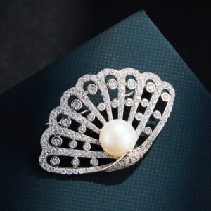 Seashell pearl crystal brooch wholesale featuring an openwork scalloped fan frame encrusted with pavé and bezel-set cubic zirconia, a center freshwater pearl, and a convertible back hook from junejewelry.com