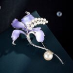 Delicate enamel lily flower pearl brooch wholesale featuring hand-applied gradient enamel petals, arched small pearl stamen cluster, and a large freshwater pearl accent on a graceful stem from junejewelry.com