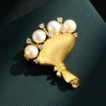 Light luxury brushed sand gold bouquet pearl brooch wholesale featuring wire-brushed matte gold wrapping, freshwater pearl blooms, and sparkling CZ accents from junejewelry.com