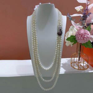 Shell pearl layered necklace wholesale featuring multi-strand white shell pearl long lariat with pavé purple and green cubic zirconia peacock clasp on palladium plated copper.