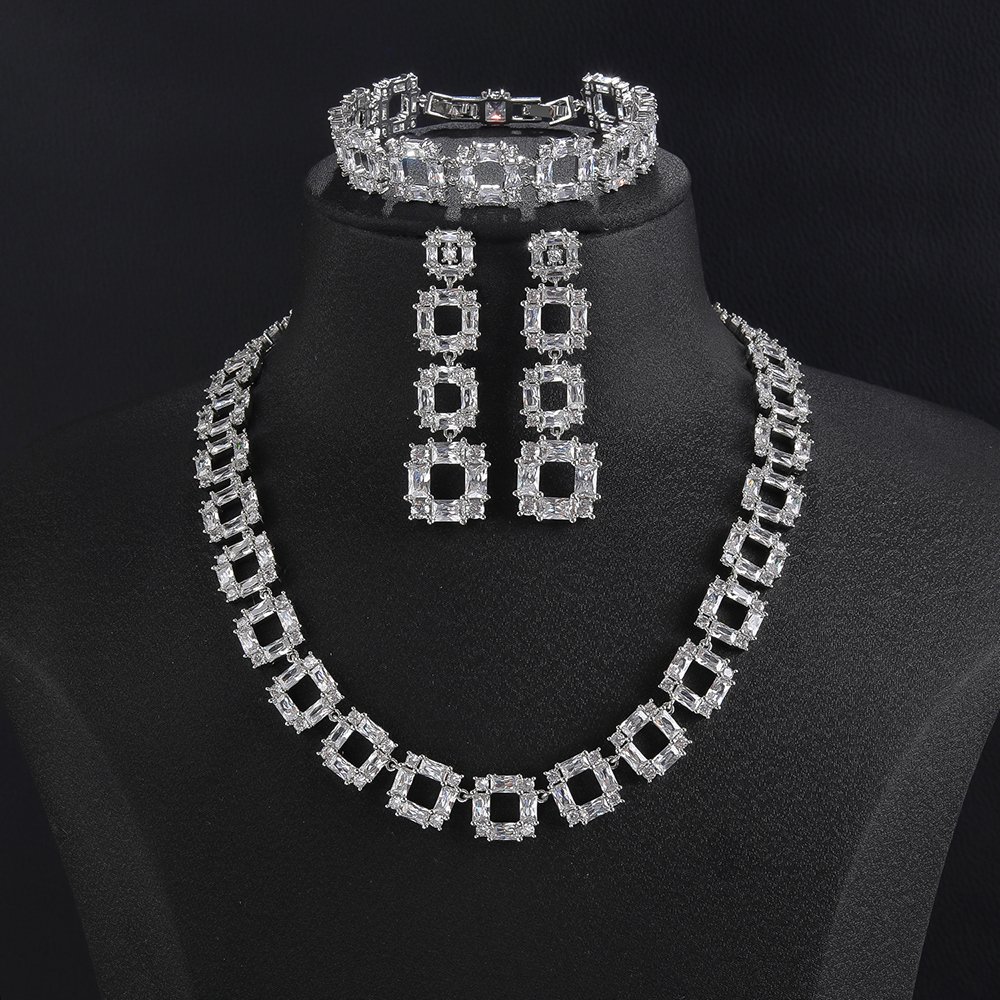 Square crystal jewelry set wholesale featuring openwork geometric square link collar necklace, long drop square earrings, and matching tennis bracelet on palladium plated copper base.