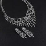 Luxury bridal crystal jewelry set wholesale featuring grand mesh lattice bib collar necklace with starburst flower centerpiece, dangling teardrop tassels, and matching drop earrings on palladium plated copper.